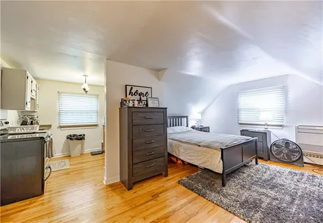 a spacious bedroom with a bed and wooden floor