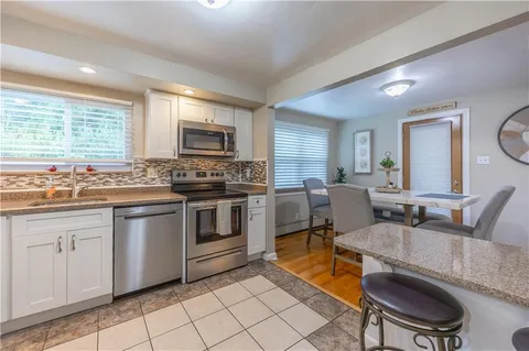 a kitchen with stainless steel appliances granite countertop a stove top oven a sink dishwasher a dining table and chairs with wooden floor