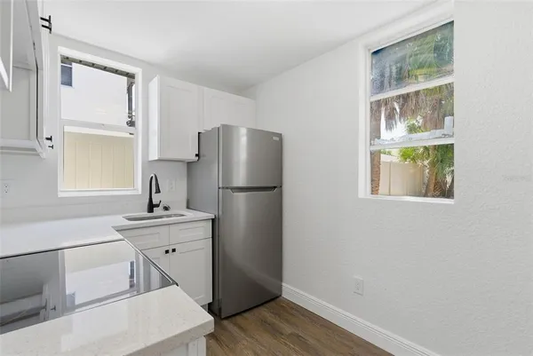 a kitchen with a sink a refrigerator and wooden floor
