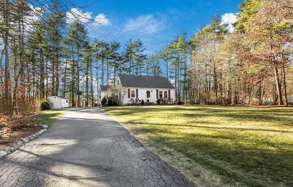 a view of a house with a yard and large trees
