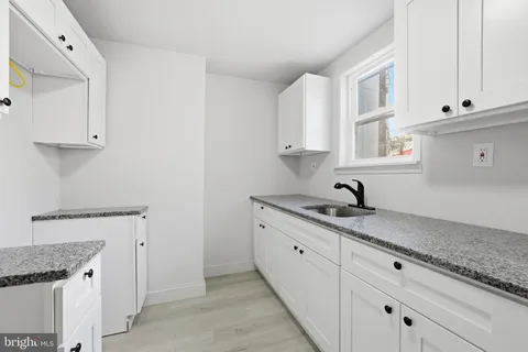 a kitchen with granite countertop white cabinets and a sink