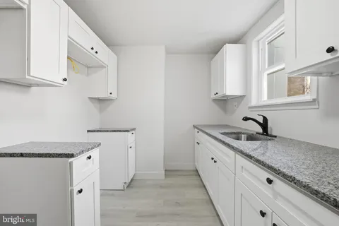 a kitchen with granite countertop white cabinets and white appliances
