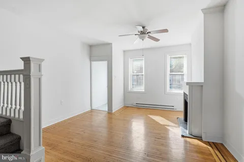 a view of empty room with wooden floor and fan