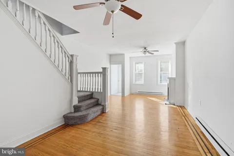 a view of an empty room with wooden floor and a chandelier