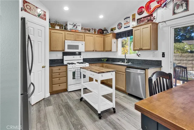 a kitchen with stainless steel appliances granite countertop a refrigerator a stove a sink dishwasher and white cabinets with wooden floor