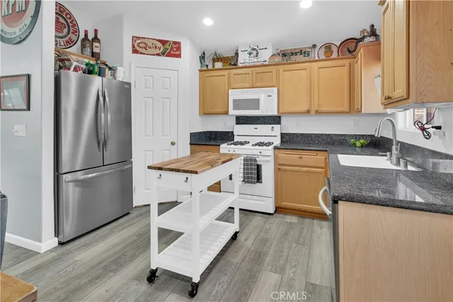 a kitchen with stainless steel appliances granite countertop a refrigerator a stove and a sink with wooden floor
