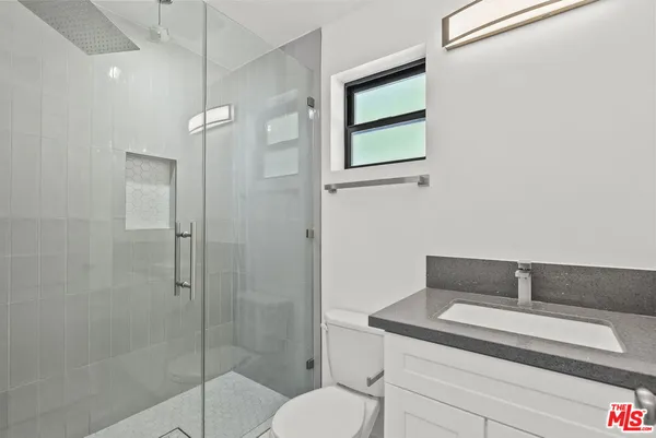 a bathroom with a toilet sink vanity and shower