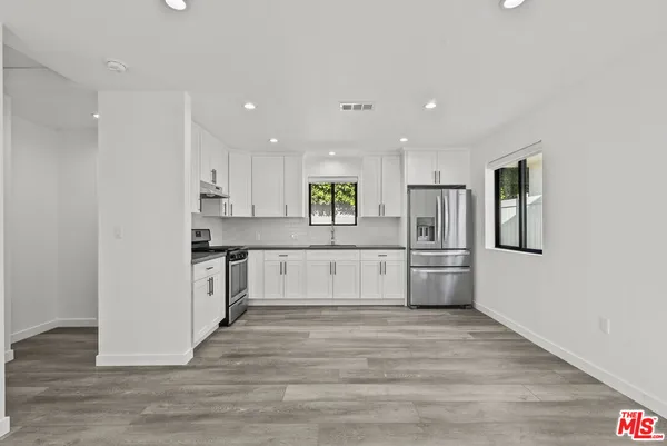 a large kitchen with stainless steel appliances granite countertop a large counter top a sink and a refrigerator