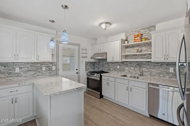 a kitchen with granite countertop white cabinets and stainless steel appliances