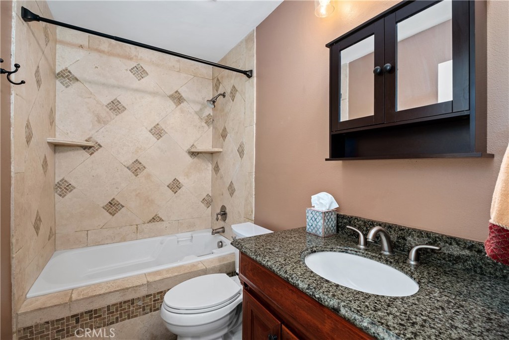 7 Oak Spring Lane, Unit 319 Aliso Viejo, CA 92656 - Photo 20 of 37 a bathroom with a granite countertop sink toilet a mirror a bathtub and shower