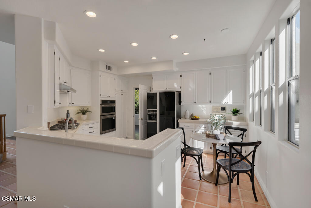 3842 Timberridge Road Moorpark, CA 93021 - Photo 21 of 75 a kitchen with stainless steel appliances kitchen island granite countertop a dining table chairs and a refrigerator