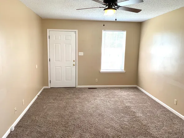an empty room with a window and a ceiling fan