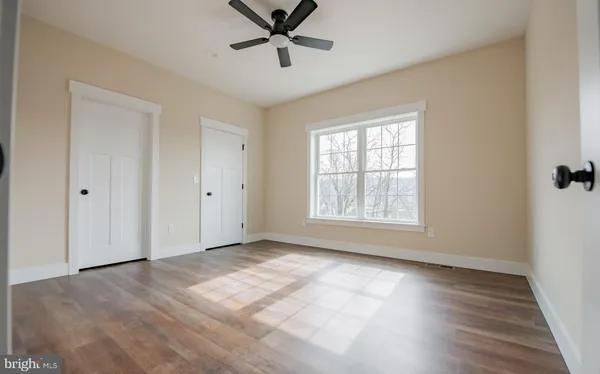 a view of empty room with wooden floor and fan
