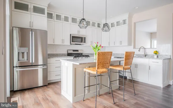 a kitchen with stainless steel appliances a refrigerator a stove a dining table and chairs with wooden floor