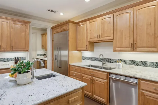 a kitchen with stainless steel appliances granite countertop a sink a stove and a granite counter tops with white cabinets