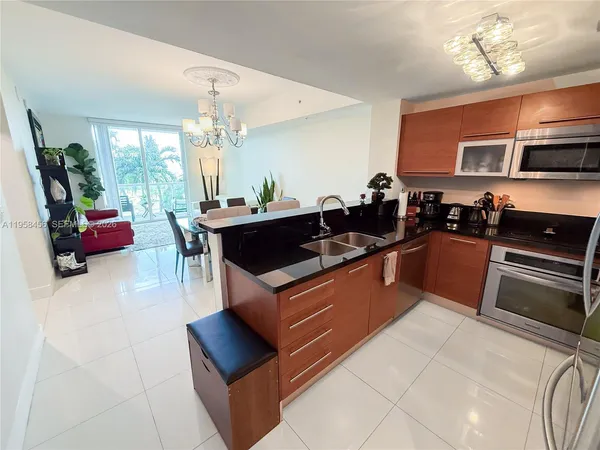 a kitchen with stainless steel appliances kitchen island granite countertop a stove a sink dishwasher and a black countertop with living room view