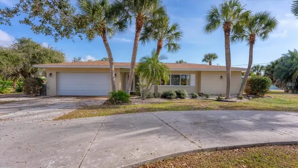 a view of a house with a yard and palm trees