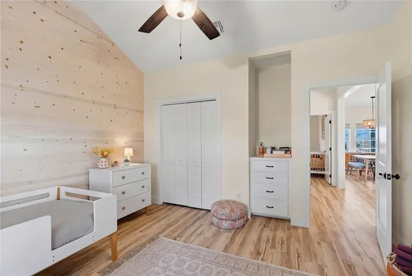 a view of a bedroom with baby crib and wooden floor