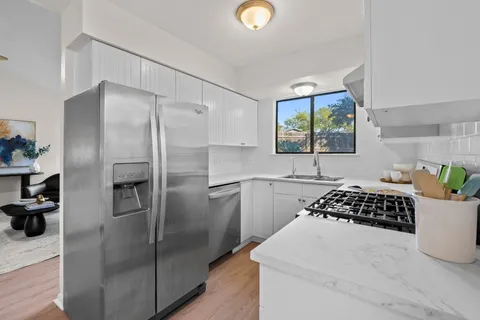 a kitchen with stainless steel appliances granite countertop a refrigerator and a stove top oven
