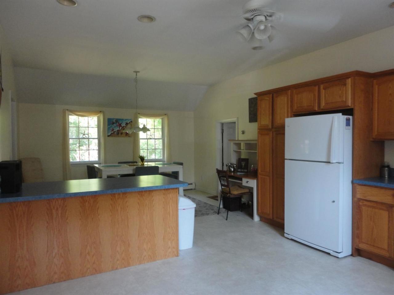 64 Elliott Road Centerville, MA 02632 - Photo 8 of 25 a large kitchen with kitchen island a counter space a refrigerator a stove a dining table and chairs