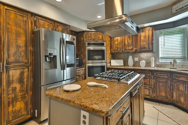 a kitchen with stainless steel appliances granite countertop a stove a sink dishwasher and a refrigerator