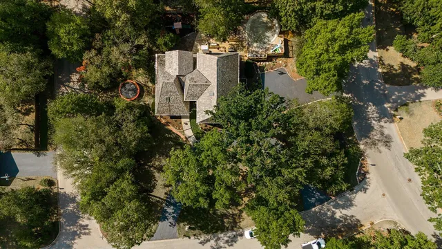 an aerial view of a house with a yard and trees all around