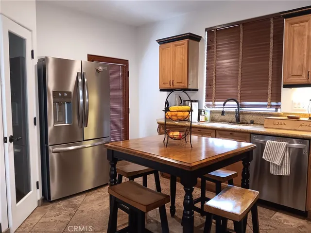 a kitchen with stainless steel appliances granite countertop a refrigerator a sink a stove and a refrigerator
