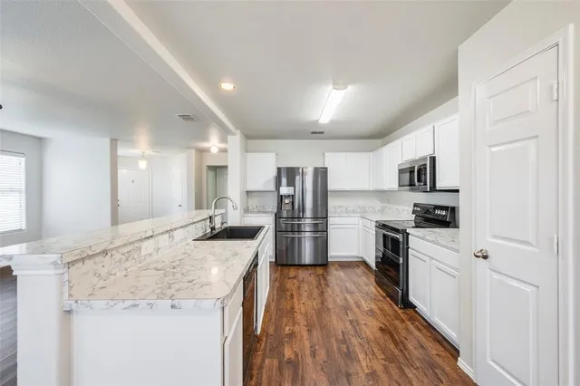 a large kitchen with granite countertop a large counter top stainless steel appliances and cabinets