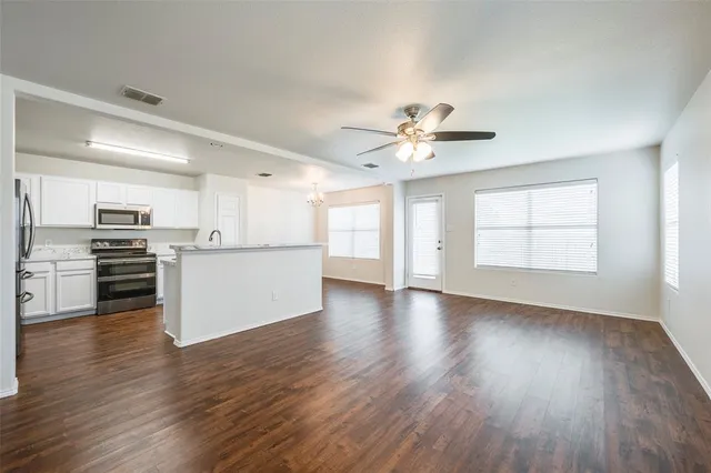 a view of an empty room with a kitchen and wooden floor