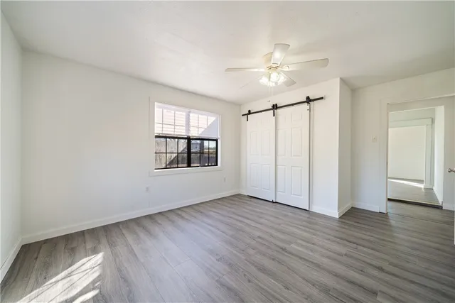 an empty room with wooden floor cabinet and windows