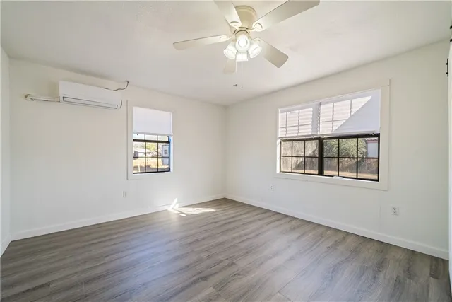 a view of an empty room with a window and wooden floor