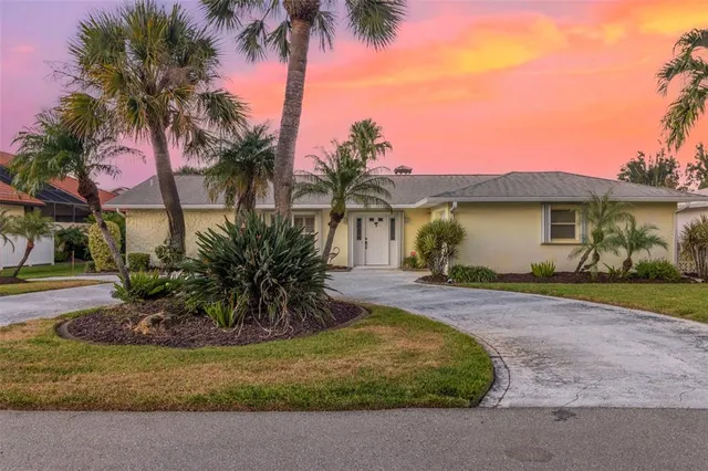 a view of a house with a yard and palm trees