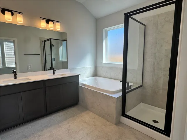 a bathroom with a double vanity sink mirror and bathtub