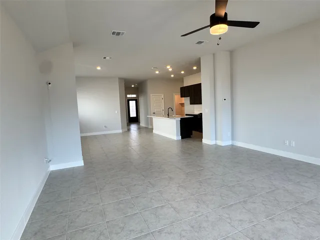 a view of an empty room and kitchen view