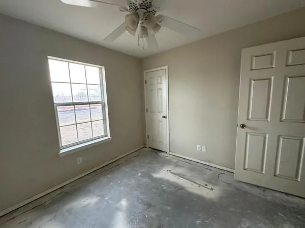 an empty room with chandelier fan and windows
