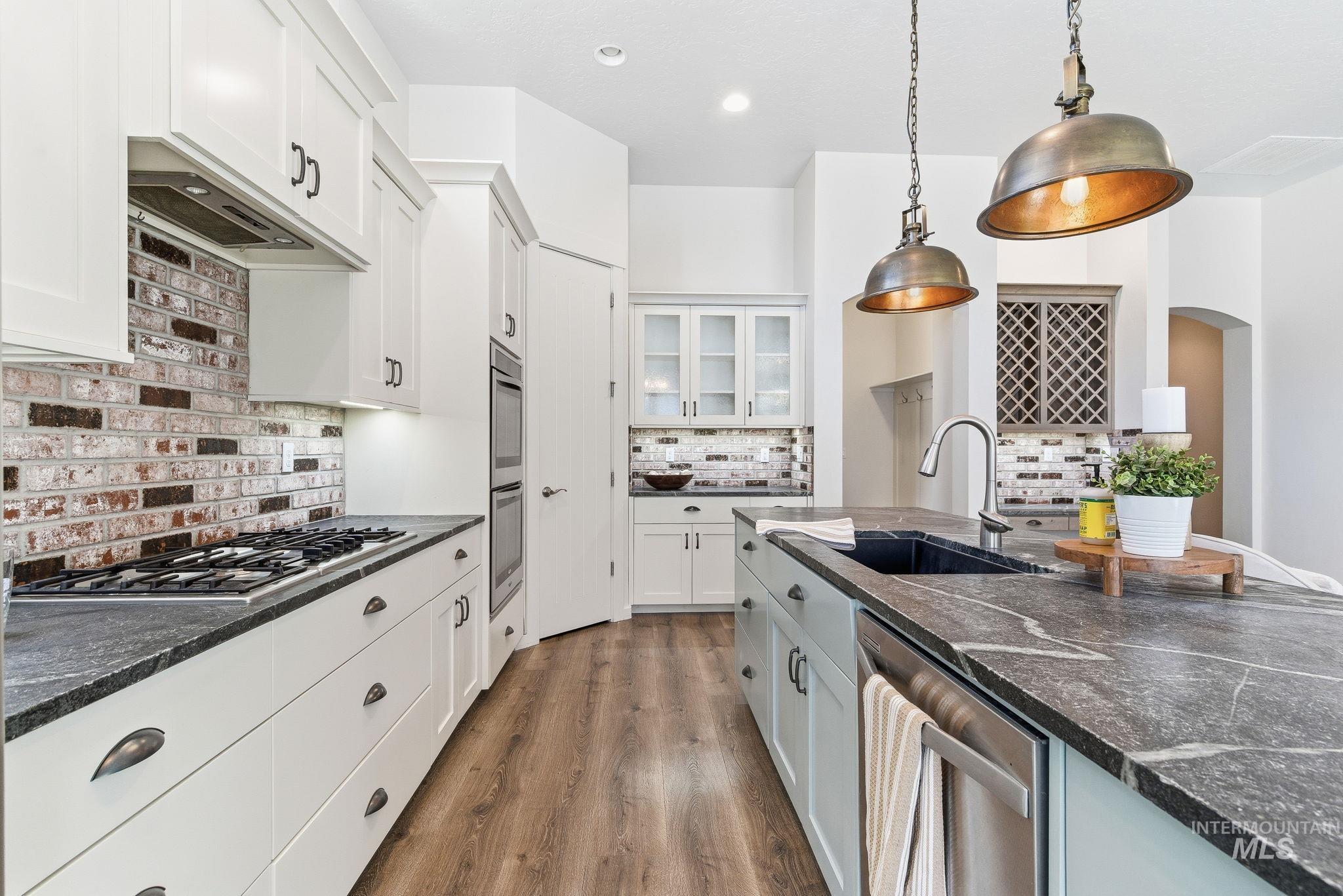 1013 East Radiant Ridge Drive Meridian, ID 83642 - Photo 11 of 36 Kitchen with appliances with stainless steel finishes, white cabinetry, dark wood-type flooring, pendant lighting, and glass insert cabinets