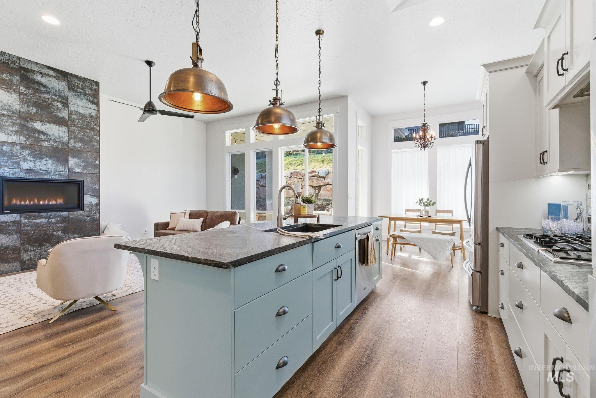 1013 East Radiant Ridge Drive Meridian, ID 83642 - Photo 14 of 36 Kitchen featuring hanging light fixtures, a center island with sink, dark wood-style floors, dark stone countertops, and recessed lighting