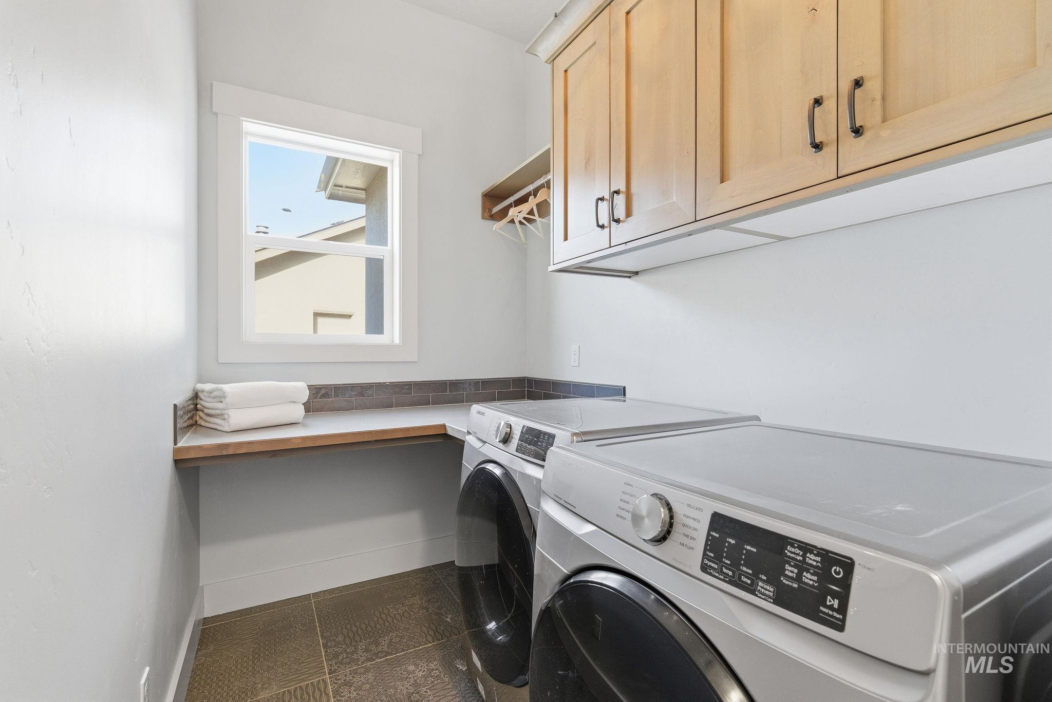 1013 East Radiant Ridge Drive Meridian, ID 83642 - Photo 27 of 36 Washroom featuring cabinet space, washing machine and clothes dryer, and dark tile patterned floors