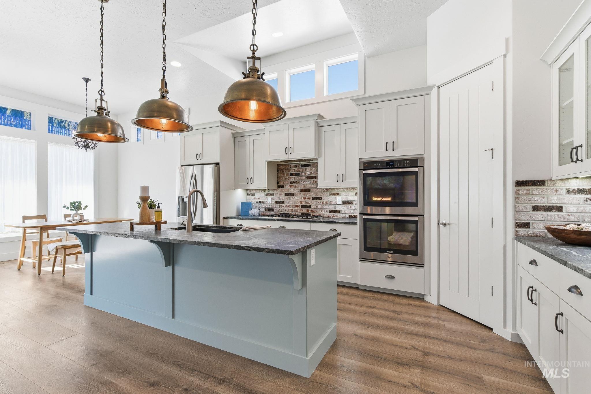 1013 East Radiant Ridge Drive Meridian, ID 83642 - Photo 8 of 36 Kitchen with appliances with stainless steel finishes, pendant lighting, a breakfast bar area, a kitchen island with sink, and light wood-type flooring
