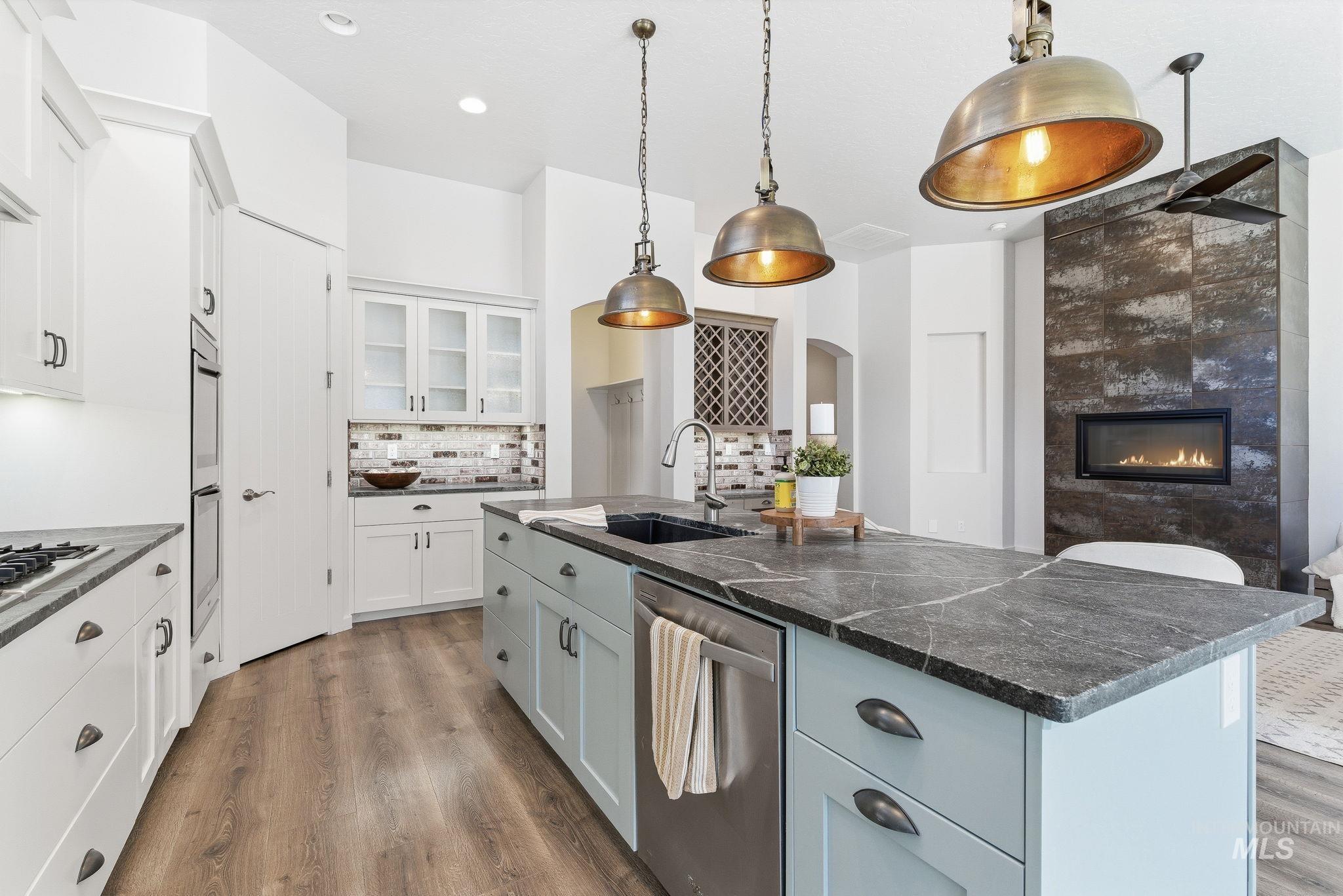 1013 East Radiant Ridge Drive Meridian, ID 83642 - Photo 10 of 36 Kitchen featuring pendant lighting, white cabinets, appliances with stainless steel finishes, and glass insert cabinets