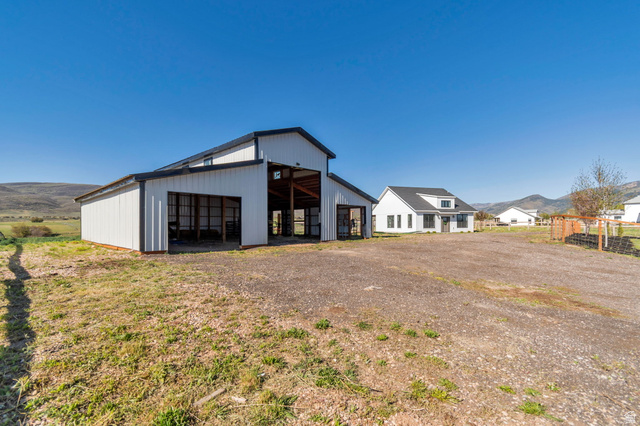 1820 West Farmhouse Flats Road Peoa, UT 84061 - Photo 76 of 79 White and black metal barn structure featuring an open-sided portion, exposed wood framing, and a gravel surface