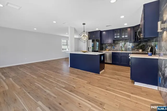 a large kitchen with stainless steel appliances granite countertop a stove and a wooden floors