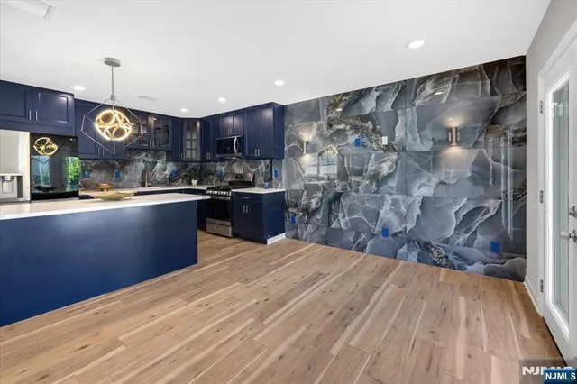 a kitchen with stainless steel appliances granite countertop a sink dishwasher a stove and a refrigerator with wooden floor