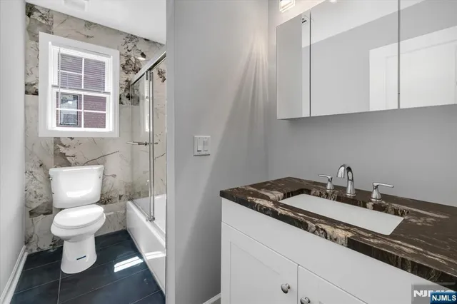 a bathroom with a granite countertop toilet sink and mirror