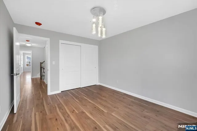 a view of a hallway with wooden floor and a chandelier