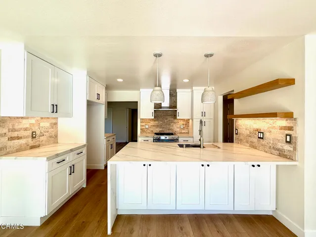 a large kitchen with stainless steel appliances kitchen island granite countertop a stove a sink and a microwave