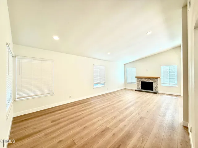 a view of empty room with wooden floor and fireplace