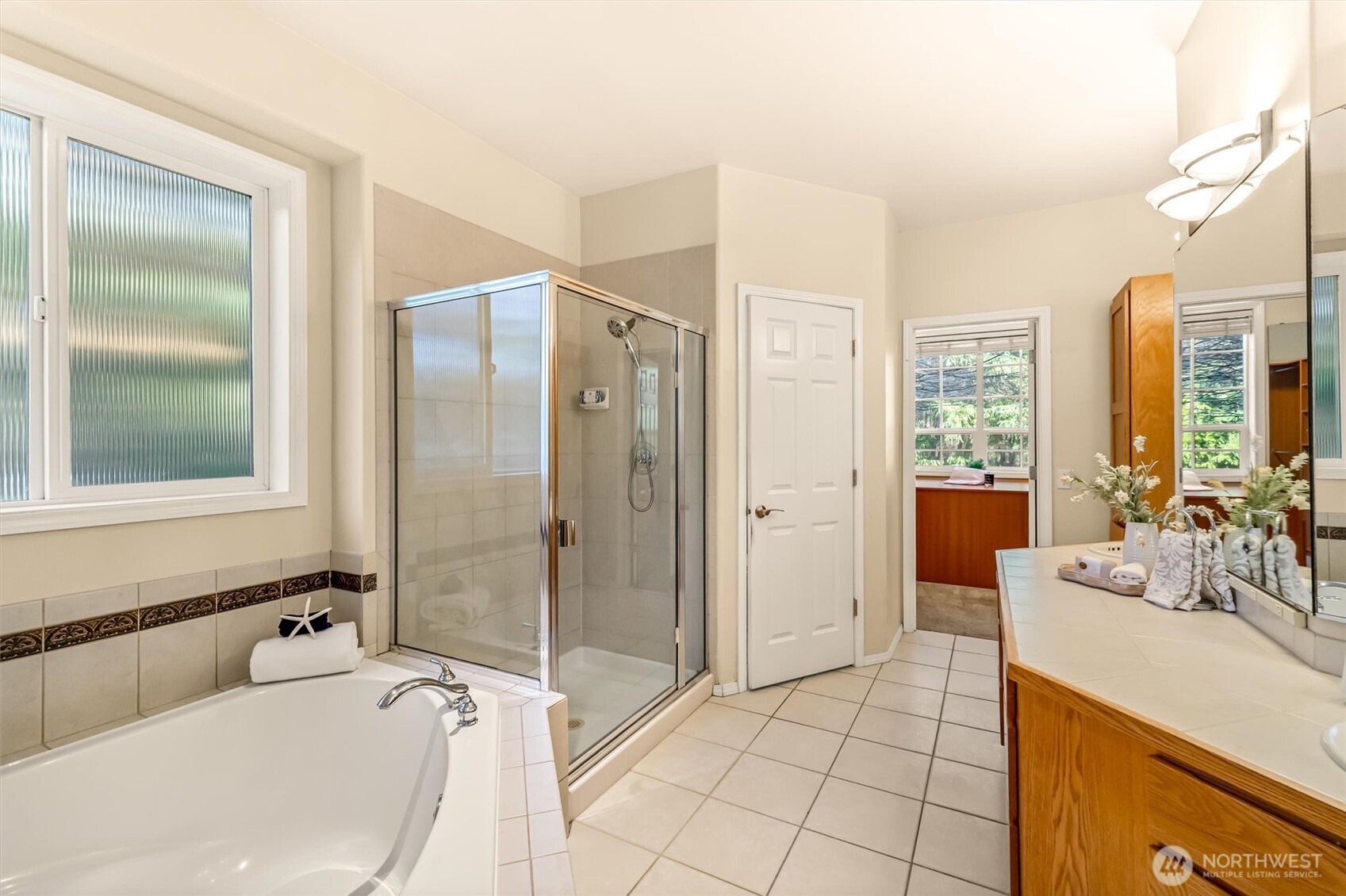 13718 58th Street Southeast Snohomish, WA 98290 - Photo 21 of 40 a bathroom with a tub a sink and a large mirror next to a window