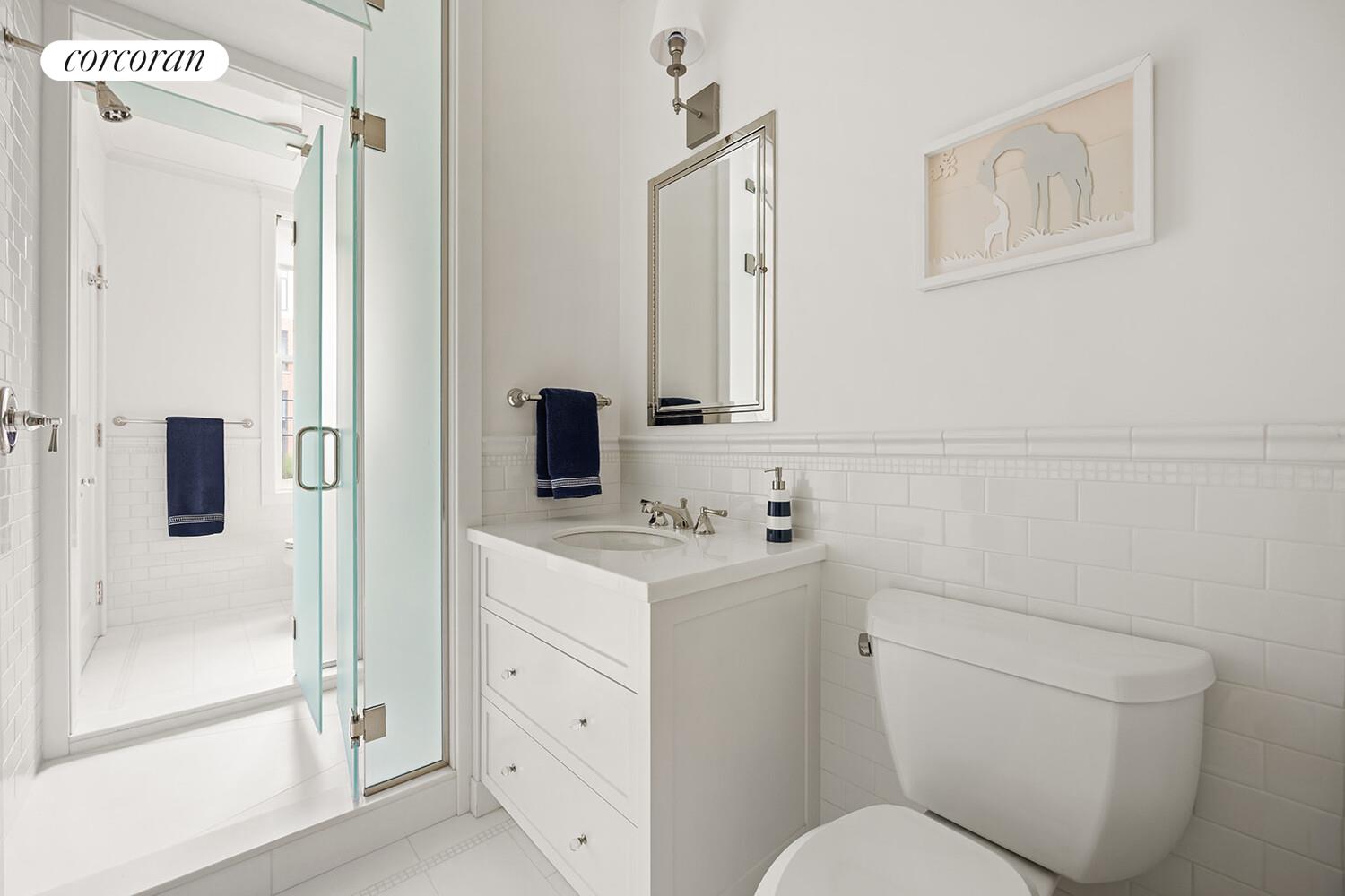 16 East 96th Street, Unit 7B Manhattan, NY 10128 - Photo 23 of 55 a bathroom with a toilet sink vanity and shower