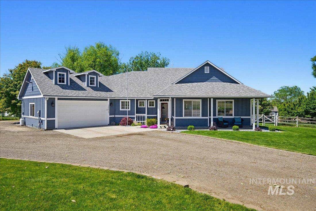 Blue exterior featuring white trim, a covered front porch, an attached garage, and dormer windows